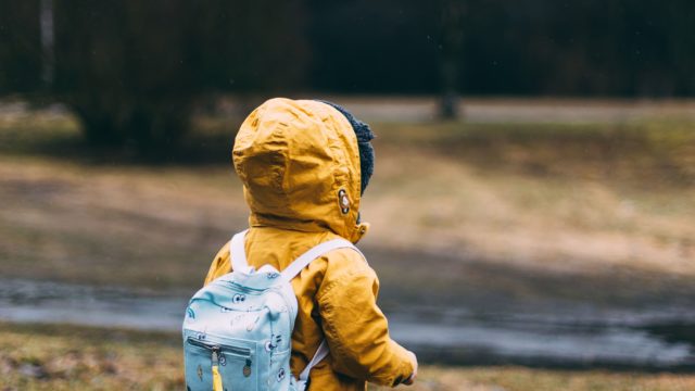 子供の男の子がリュック背負って公園を歩いている-min